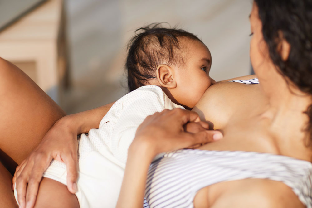 Baby breastfeeding while held in mother's arms