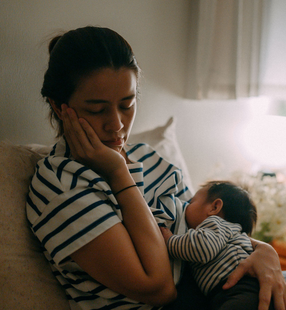 Tired mother holding and breastfeeding her baby